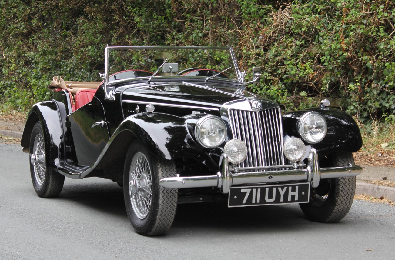 Black 1950s MG TF roadster with red interior and chrome wire wheels, registration 711 UYH
