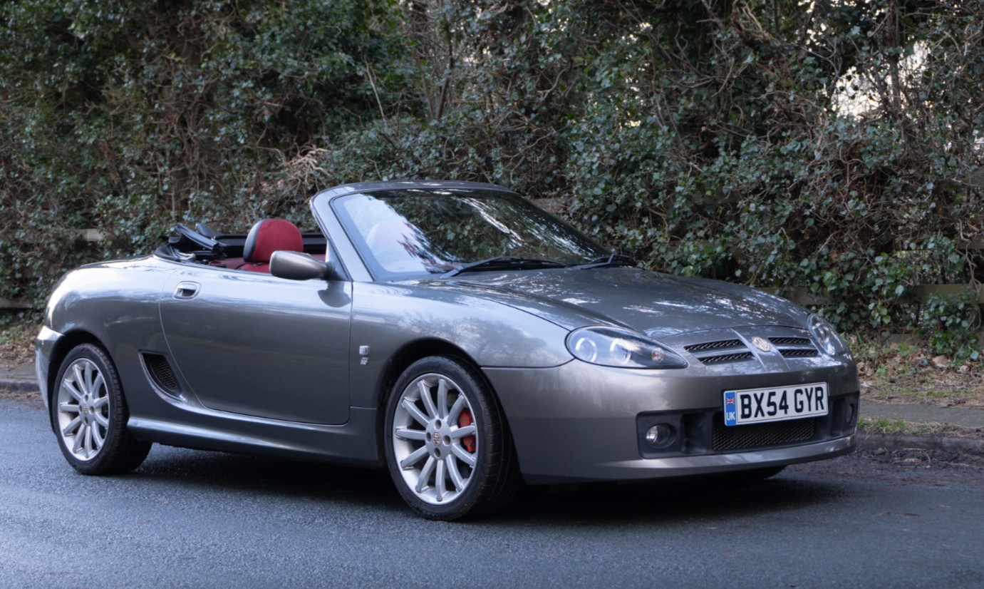 A 2004 MG TF 135 in XPower Grey with red leather, roof down, showing the modern mid-engined roadster profile