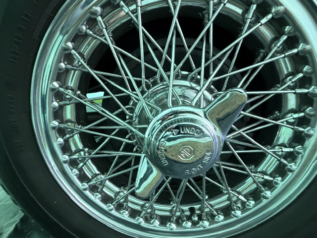 Close-up of a chrome centre-lock wire wheel on a cream MG TF 1500, with the octagon-eared knock-off spinner marked Undo and Right Side