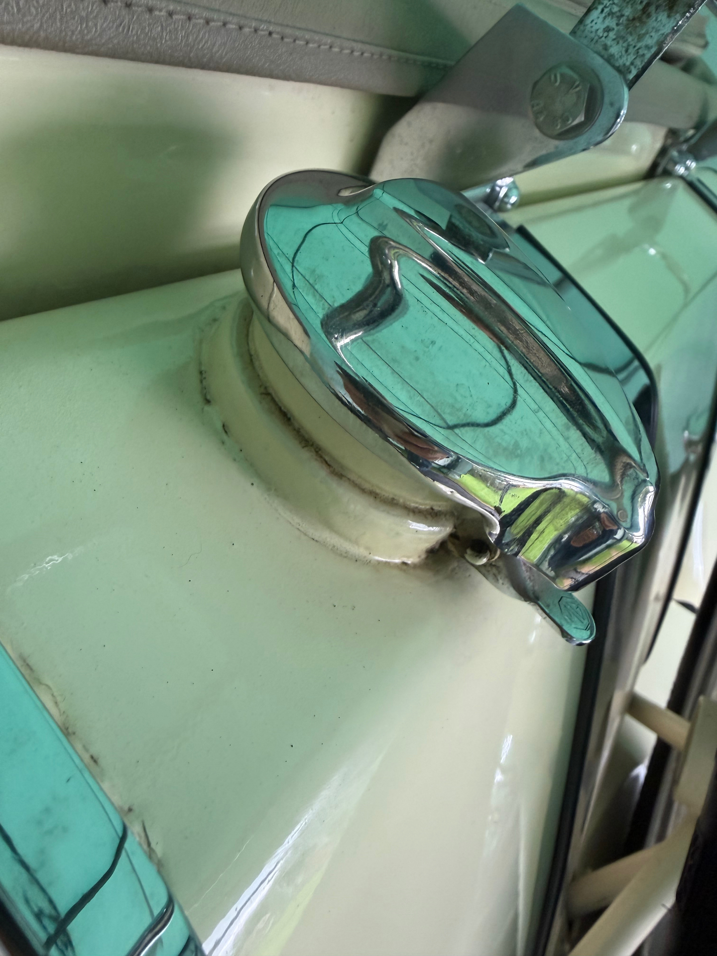 Chrome fuel filler cap on a cream MG TF body, with a leather retaining strap and bright chrome finish visible