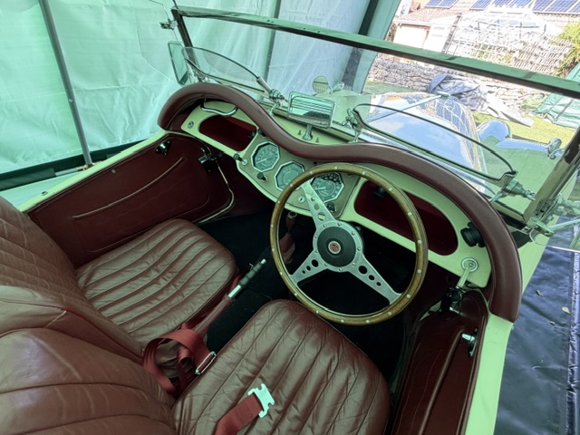 Wide view of the MG TF 1500 cockpit from the driver's door, showing the maroon leather individual seats and dashboard layout