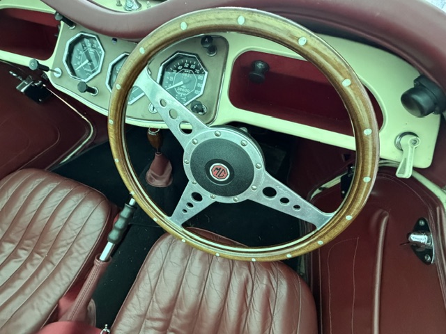 Interior view of an MG TF 1500 looking through the wooden-rimmed steering wheel at the octagonal Smiths instruments