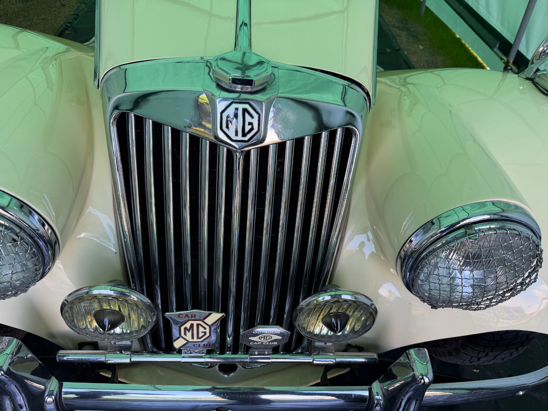 Front view of a cream MG TF 1500 chrome radiator grille with the MG octagon badge and two auxiliary fog lamps